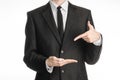 Businessman and gesture topic: a man in a black suit with a tie shows the left hand index finger on his right hand on a white Royalty Free Stock Photo