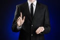 Businessman and gesture topic: a man in a black suit and white shirt showing gestures with hands on a dark blue background in stud Royalty Free Stock Photo