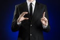 Businessman and gesture topic: a man in a black suit and white shirt showing gestures with hands on a dark blue background in stud Royalty Free Stock Photo