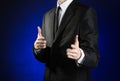 Businessman and gesture topic: a man in a black suit and white shirt showing gestures with hands on a dark blue background in stud Royalty Free Stock Photo