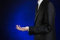 Businessman and gesture topic: a man in a black suit and white shirt showing gestures with hands on a dark blue background in stud Royalty Free Stock Photo