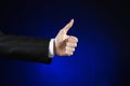 Businessman and gesture topic: a man in a black suit and white shirt showing hand gesture on an isolated dark blue background in Royalty Free Stock Photo