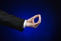 Businessman and gesture topic: a man in a black suit and white shirt showing hand gesture on an isolated dark blue background in Royalty Free Stock Photo