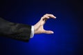 Businessman and gesture topic: a man in a black suit and white shirt showing hand gesture on an isolated dark blue background in Royalty Free Stock Photo