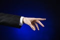 Businessman and gesture topic: a man in a black suit and white shirt showing hand gesture on an isolated dark blue background in Royalty Free Stock Photo