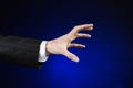 Businessman and gesture topic: a man in a black suit and white shirt showing hand gesture on an isolated dark blue background in Royalty Free Stock Photo