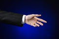 Businessman and gesture topic: a man in a black suit and white shirt showing hand gesture on an isolated dark blue background in Royalty Free Stock Photo