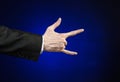 Businessman and gesture topic: a man in a black suit and white shirt showing hand gesture on an isolated dark blue background in Royalty Free Stock Photo