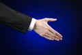 Businessman and gesture topic: a man in a black suit and white shirt showing hand gesture on an isolated dark blue background in Royalty Free Stock Photo