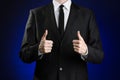 Businessman and gesture topic: a man in a black suit and white shirt showing hand gestures a thumbs-up on a dark blue background Royalty Free Stock Photo