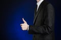 Businessman and gesture topic: a man in a black suit and white shirt showing hand gestures a thumbs-up on a dark blue background Royalty Free Stock Photo