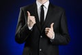 Businessman and gesture topic: a man in a black suit and white shirt showing hand gestures a thumbs-up on a dark blue background Royalty Free Stock Photo