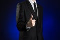 Businessman and gesture topic: a man in a black suit and white shirt showing a thumbs up hand on a dark blue background in studio Royalty Free Stock Photo