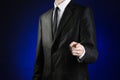 Businessman and gesture topic: a man in a black suit and white shirt shows his hand forward on a dark blue background in studio is Royalty Free Stock Photo