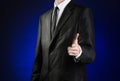 Businessman and gesture topic: a man in a black suit and white shirt shows his hand forward on a dark blue background in studio is Royalty Free Stock Photo