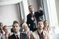 Businessman gesturing while asking question during seminar in convention center