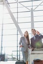 Businessman gesturing and talking to young attractive businesswoman  while queuing for check in at airport Royalty Free Stock Photo