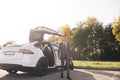 Businessman gets out of a white executive car at car park during day time. The business person is came to the workplace