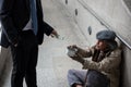 Businessman give 2 dollar bills to beggar in city