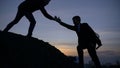 Businessman silhouette gived hand for pull team to peak mountain work together