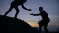 Businessman silhouette gived hand for pull team to peak mountain work together