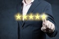 Hand of businessman touching five star symbol to increase rating of company concept. Businessman giving a five star rating on blue Royalty Free Stock Photo