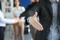 Businessman giving his hand for handshake to partner against background of colleagues closeup Royalty Free Stock Photo