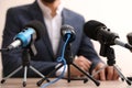Businessman giving interview at table with microphones, closeup