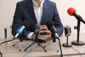 Businessman giving interview at table with microphones. Journalist conference