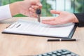 Businessman giving key over loan agreement document with calculator on wooden desk. Royalty Free Stock Photo