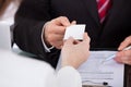 Businessman giving visiting card to colleague at desk Royalty Free Stock Photo