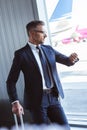 businessman in glasses standing at departure lounge near window and looking at watch Royalty Free Stock Photo