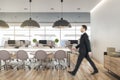 Businessman goes by conference table in modern eco style open space office with wooden decor elements Royalty Free Stock Photo