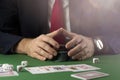 Businessman at green gaming table with game chips, cards and dice playing poker and blackjack in casino Royalty Free Stock Photo