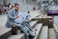 businessman in grey suit reading newspaper on stairs Royalty Free Stock Photo