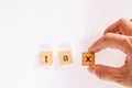 Businessman hand creates the word `tax` of the wooden letter blocks on a white background. Royalty Free Stock Photo