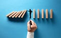 Businessman hand drawing silhouette of a man making a stop gesture to prevent wooden dominos from collapsing