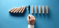 Businessman hand drawing silhouette of a man making a stop gesture to prevent wooden dominos from collapsing