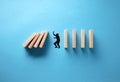 Businessman hand drawing silhouette of a man in panic against collapsing wooden dominos on blue background. Business crisis and