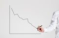 Businessman hand draws a declining line graph