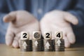 Businessman hand give wooden block cube 2024 with dartboard on coins stacking for setup objective target business cost and budget