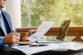 Businessman hand holding coffee cup, analysis the graph with laptop at the home office for setting challenging business goals And Royalty Free Stock Photo