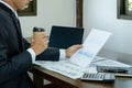 Businessman hand holding coffee cup, analysis the graph with laptop at the home office for setting challenging business goals And Royalty Free Stock Photo