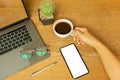 Businessman hand holding coffee cup with laptop and eyeglasson wooden desk. Royalty Free Stock Photo