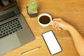 Businessman hand holding coffee cup with laptop and pen on wooden desk. Royalty Free Stock Photo