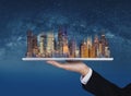 Businessman hand holding digital tablet with modern buildings hologram. Smart city, building technology and real estate business Royalty Free Stock Photo