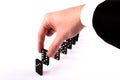 Businessman hand holding domino and row of dominoes isolated on white background Royalty Free Stock Photo
