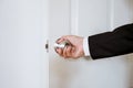 Businessman hand holding door knob, opening or closing door, with bright behind the door