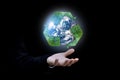 Businessman hand holding Earth and recycle logo over black background. Royalty Free Stock Photo