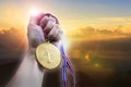 Businessman hand holding golden coin medal on hill. Royalty Free Stock Photo